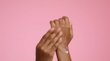 African American Woman Applying Moisturizer On Hands, Pink Background, Cropped