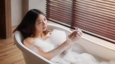 Beautiful Young Asian Female Washing Body With Soap While Relaxing In Bathtub