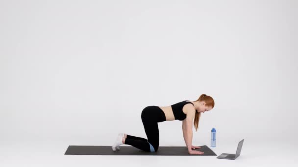 Sporty woman training with elastic band in front of laptop in studio — Wideo stockowe