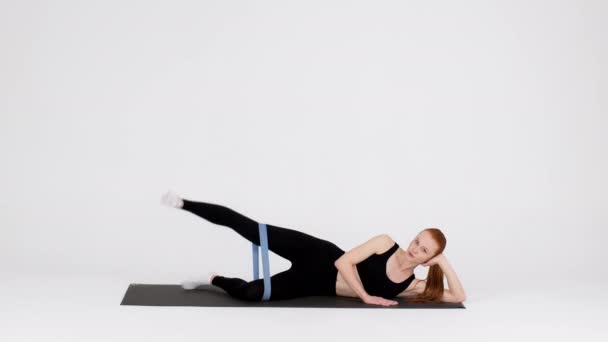 Woman Making Side Leg Lift Exercise With Elastic Rubber Band In Studio — Stok video