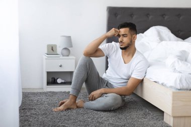 Melancholy Concept. Thoughtful Upset Arab Man Sitting On Floor In Bedroom