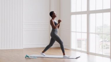 Sporty black woman making lunges exercise while training at home