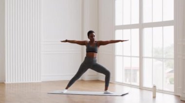 Slim Sporty African American Woman Practicing Yoga, Making Warrior 2 Pose