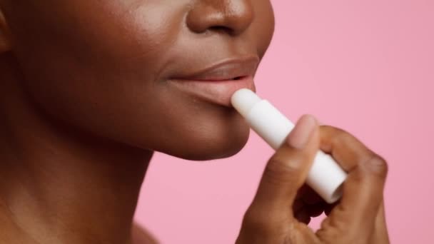 Unrecognizable African American Lady Applying Lip Balm Over Pink Background — Stockvideo