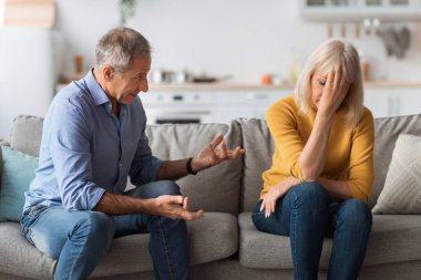 Mature Couple Having Conflict, Husband Talking To Offended Wife Indoors