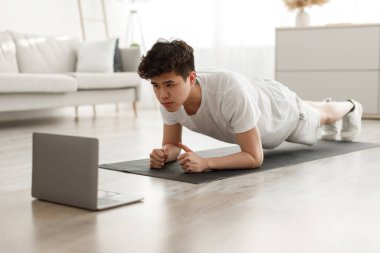 Sportif Asyalı adam dizüstü bilgisayarda kalas izleme dersi veriyor.