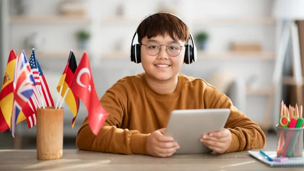 Positive chinese kid with wireless headset and digital tablet — Stockfoto