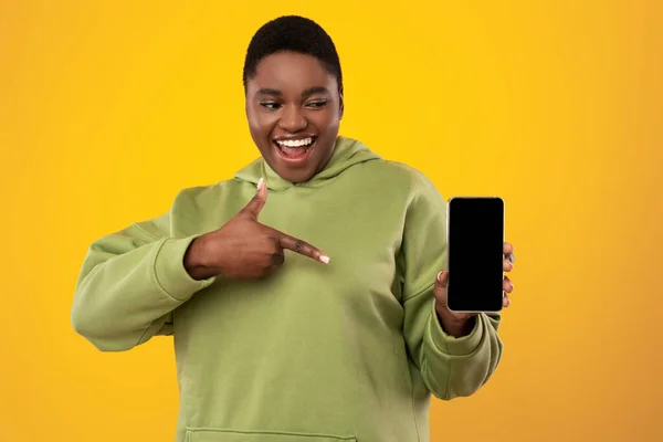 African American Woman Showing Blank Smartphone Screen Over Yellow Background — стокове фото