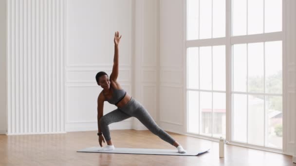 年轻黑人妇女在家练习瑜伽时做伸展三角裤 — 图库视频影像