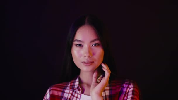 Сексуальна молода красива азіатка торкається волосся і дивиться на камеру — стокове відео