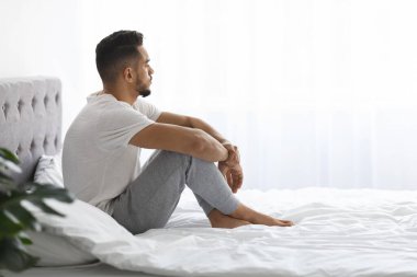 Melancholy. Young Pensive Middle Eastern Man Sitting In Bed And Looking Away