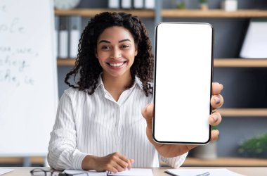 E-Learning Concept. Smiling Black Female Tutor Showing Big Blank Smartphone At Camera