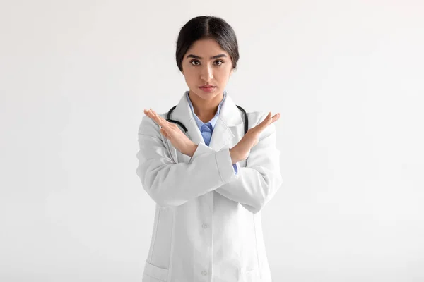 Unhappy millennial cute hindu female medical worker in uniform say no, cross arms isolated on white background — Stock Fotó