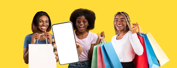 Fancy african american females shopaholics showing smartphone with blank screen — 스톡 사진