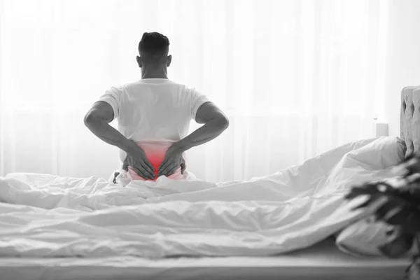 Unrecognizable Man Suffering Lower Back Pain While Sitting On Bed At Home — Stock fotografie