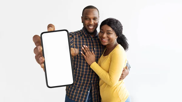 Beautiful african american lovers showing cellphone with empty screen — Stok fotoğraf