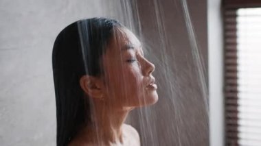 Japanese Woman Taking Shower With Eyes Closed Standing In Bathroom