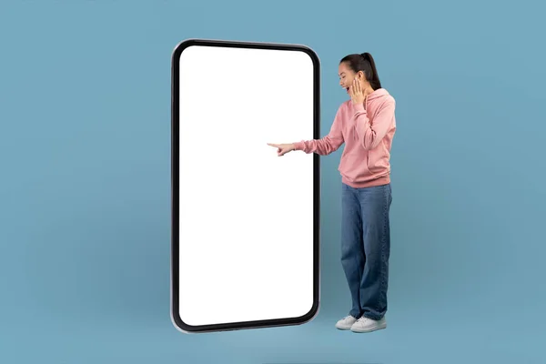Excited korean millennial woman pointing at big smartphone screen — стокове фото