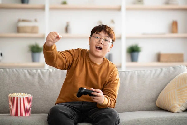 Emocional asiático chico jugando de mano video juego en casa — Foto de Stock
