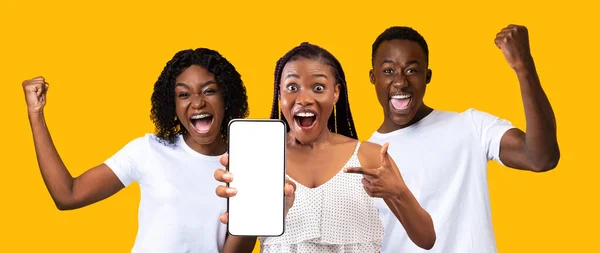 Happy black guy, two ladies showing smartphone with empty screen — Foto de Stock