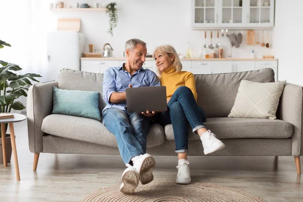 Senior Couple Using Laptop Computer Sitting On Couch At Home — Zdjęcie stockowe