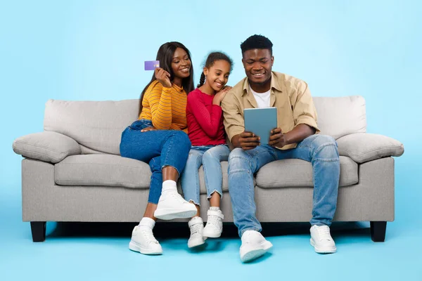 Happy black family using tablet and credit card — Stockfoto