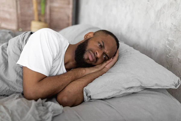 Hombre negro acostado en la cama y pensando — Foto de Stock