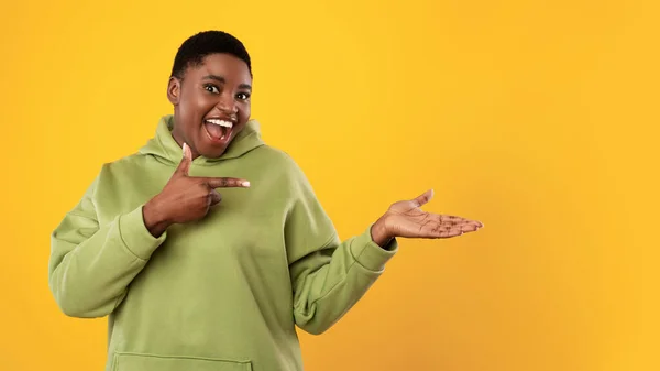African Lady Pointing Finger At Palm Of Hand, Yellow Background — Stockfoto