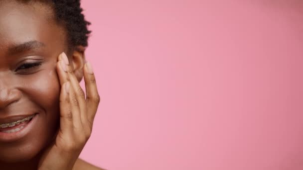 Half-Portrait Of Black Woman Applying Moisturizer On Face, Pink Background — Stok video
