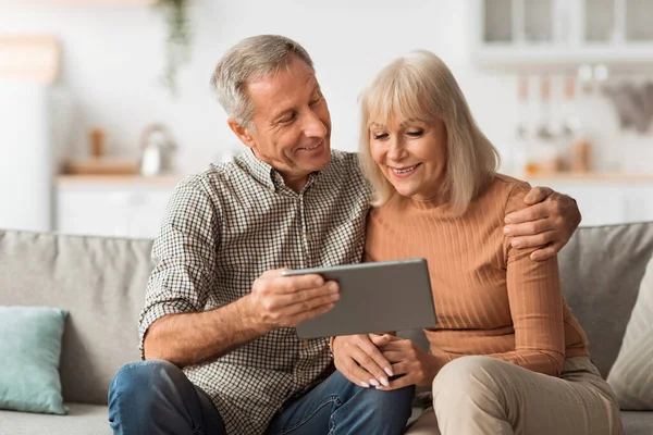 Senior Spouses Watching Movie On Tablet Embracing Sitting At Home — Stock fotografie