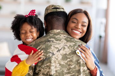 Homecoming Concept. American Soldier Embracing Wife And Daughter After Returning From Army