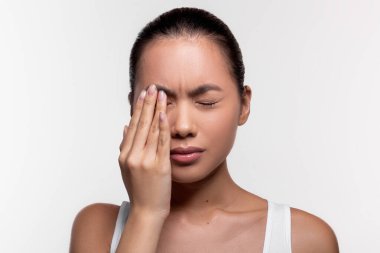 Upset asian woman suffering from strong eye pain