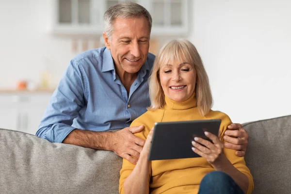 Smiling Older Couple Using Tablet Computer Watching Movie Online Indoor — Fotografia de Stock