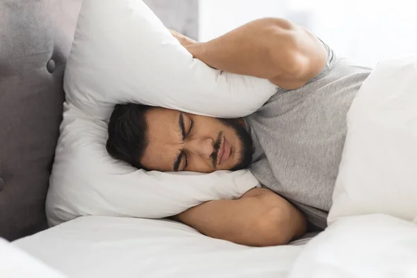 Insomnia Concept. Annoyed Middle Eastern Guy Covering Ears With Pillow — Stock fotografie