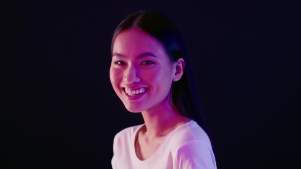Half-Turned Asian Female Laughing At Camera While Standing Illuminated By Neon Light — 비디오