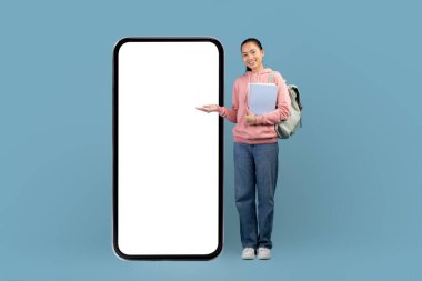 Pretty asian student with backpack and books standing by cellphone