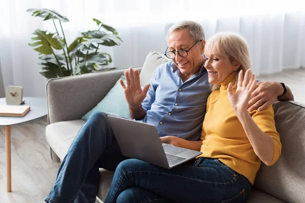 Mature Couple Waving Hands Video Calling Via Laptop At Home — Stock fotografie