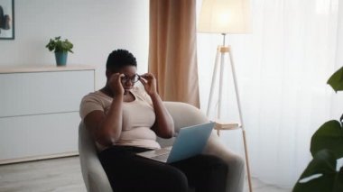 African Woman Using Laptop Taking-Off Eyeglasses Having Sore Eyes Indoor