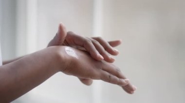 Unrecognizable African American Woman Applying Moisturizer On Hands At Home