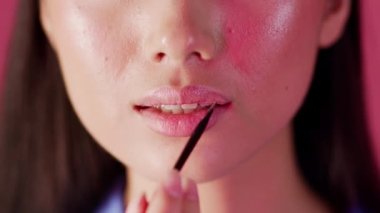 Closeup Shot Of Young Woman Applying Lip Gloss With Makeup Brush