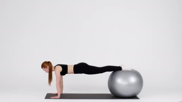 Young Sporty Woman Making Plank Exercise While Balancing On Fitball In Studio — Stockvideo