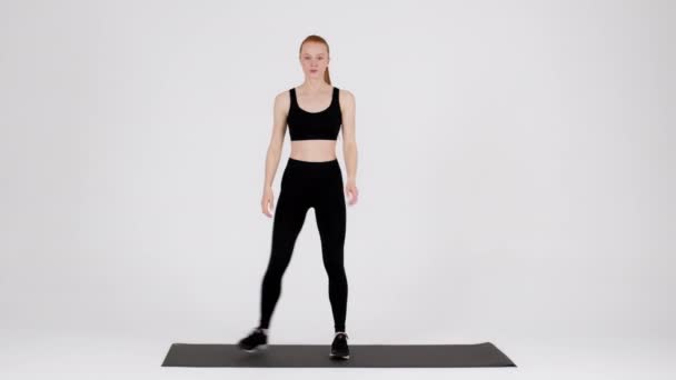 Athletic young female in sportswear making side lunges exercise in studio — Vídeos de Stock