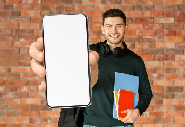 Навчальний додаток. Щасливий Чоловік Студент демонструє великий порожній смартфон на камеру, макет — стокове фото