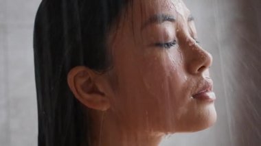 Chinese Young Lady Taking Shower Closing Eyes In Bathroom Indoors