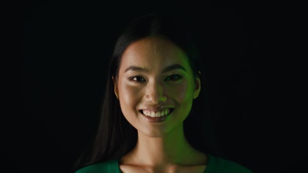 Face Of Young Beautiful Smiling Asian Woman Illuminated By Green Neon Light — стокове відео