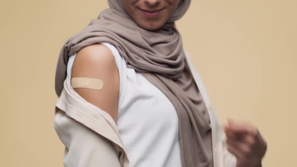 Unrecognizable muslim woman demonstrating shoulder with medical plaster after vaccination and gesturing thumb up — Video Stock