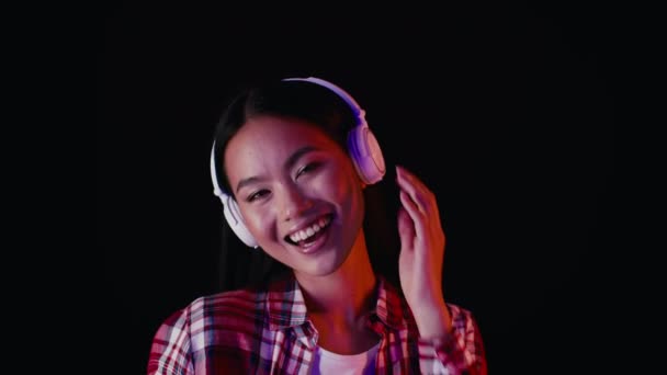 Портрет щасливої молодої азіатки слухати музику в бездротових навушниках — стокове відео