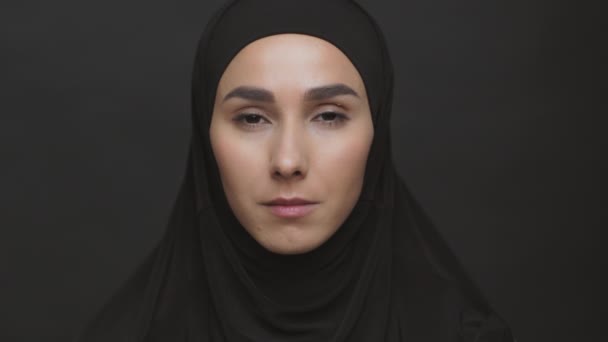 "Female rights discrimination in muslim world". Jeune femme sérieuse du Moyen-Orient portant hijab noir regardant à la caméra — Video