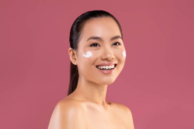 Beautiful asian woman with moisturizer cream on her cheeks