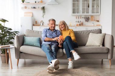 Happy Mature Husband And Wife Using Smartphone Sitting At Home